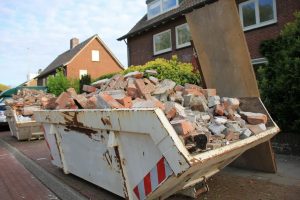 Overflowing construction dumpster filled with brick and concrete debris on a residential street.